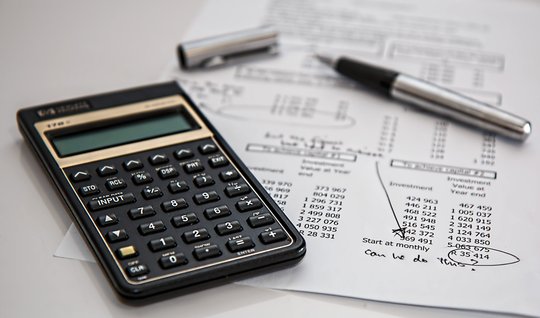 Calculator, pen and investment projections on a desk