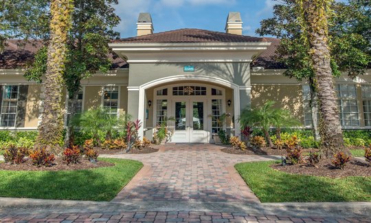 Clubhouse entrance framed by palm trees at a multifamily property