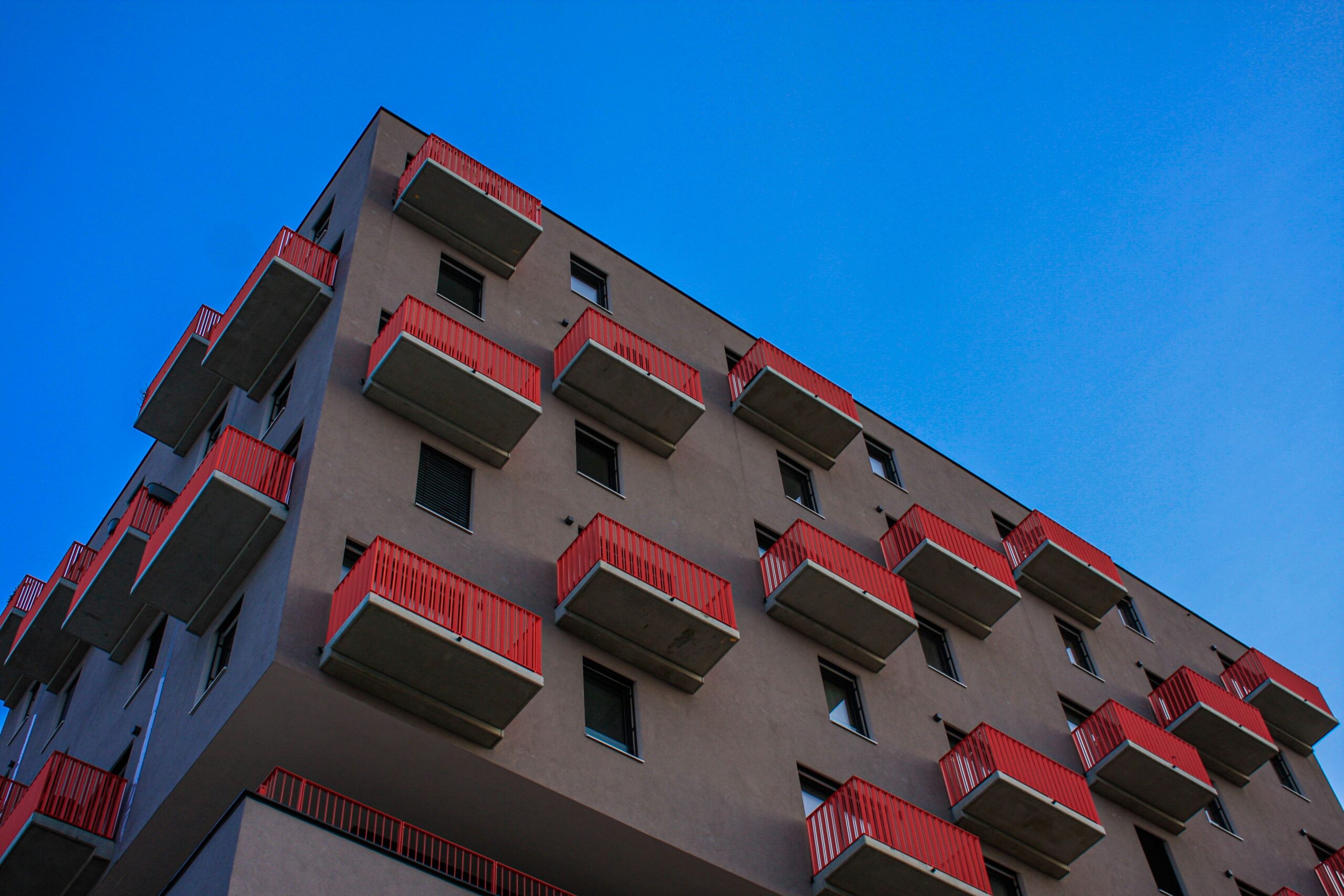 Apartment building with red balconies against blue sky